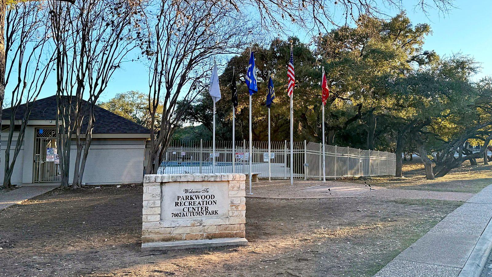 Parkwood Recreation Center sign at 7602 Autumn Park with flags and the community pool behind it